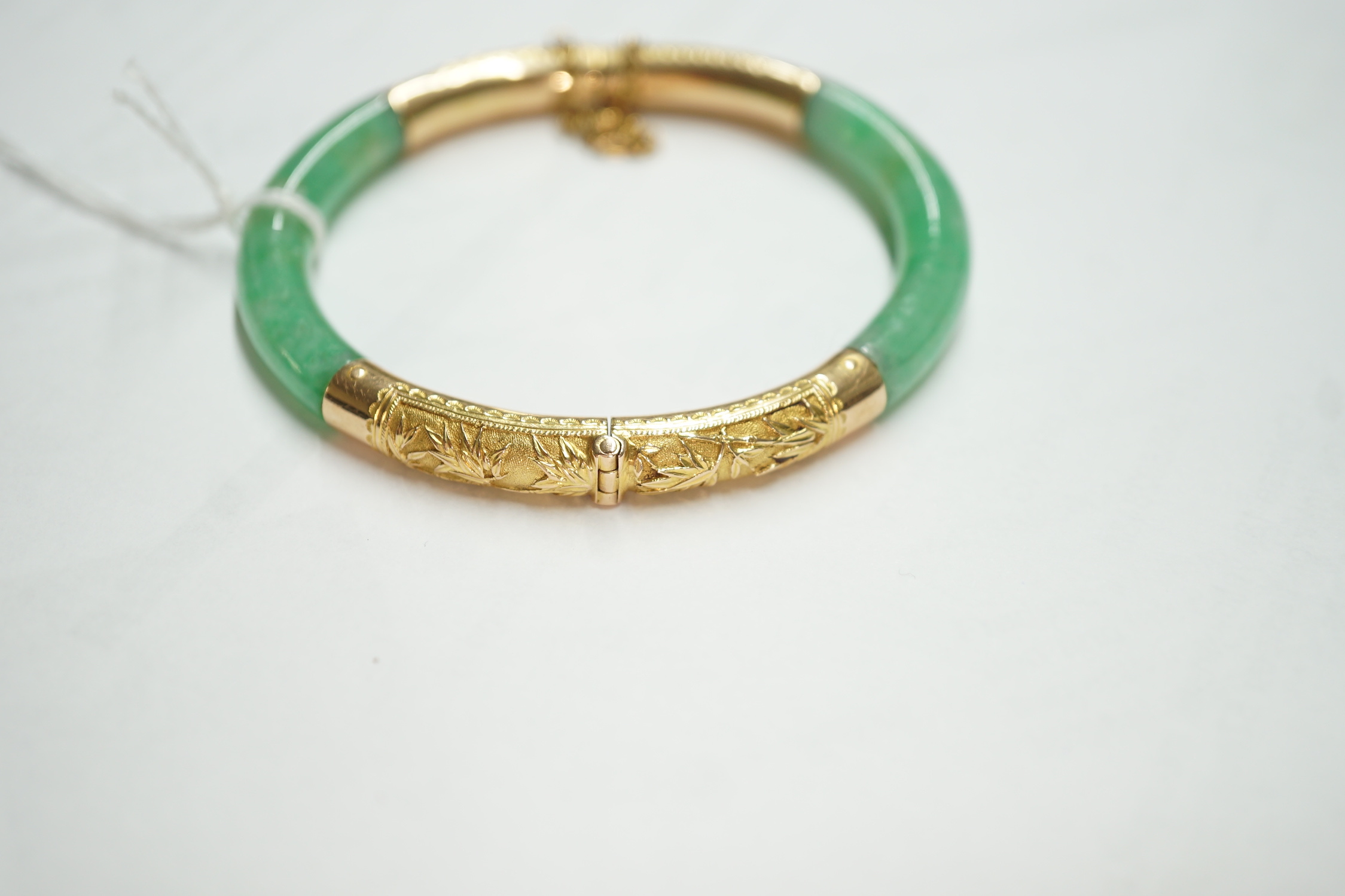 A Chinese 18k yellow metal mounted hinged bangle, interior diameter 57mm, gross weight 29.5 grams.